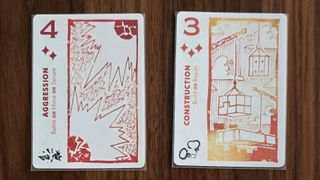 Two white and red cards from Arcs, laid out beside each other on a wooden surface